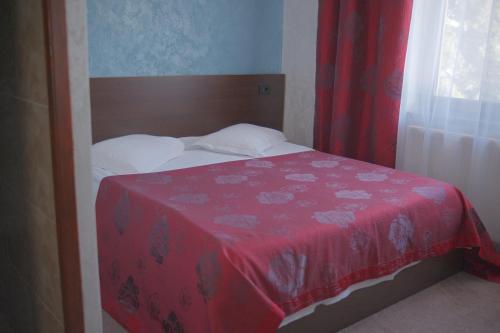 1 dormitorio con 1 cama con manta roja y ventana en Pensiunea La Busu, en Bran