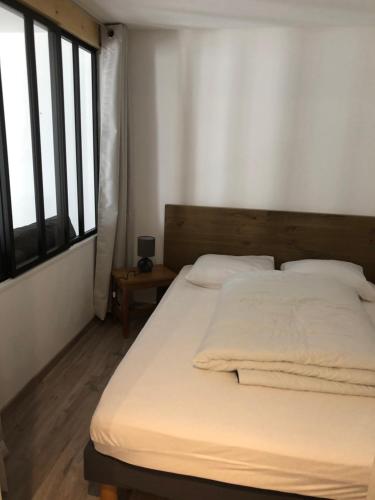 een slaapkamer met een bed met witte lakens en een raam bij Gite La Barthe Basse in Le Pont-de-Montvert