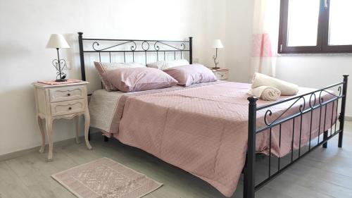 a bedroom with a black bed with pink sheets and pillows at L'Ajaccio B&B in La Maddalena