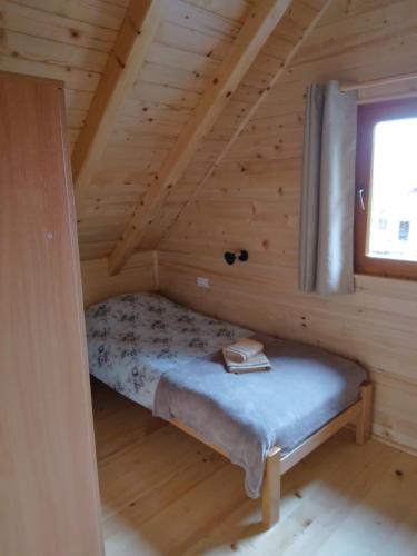 Cama pequeña en una cabaña de madera con ventana en Brvnara Srna Zlatar en Nova Varoš