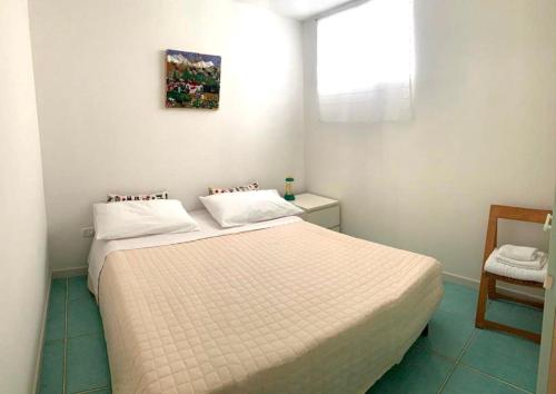 1 dormitorio con 1 cama blanca y 1 silla en Il Giardino di Elettra, en Palmadula