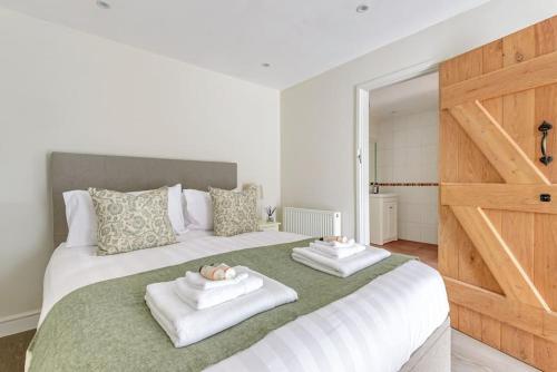 a bedroom with a large bed with two towels at The Cowshed in Farmborough