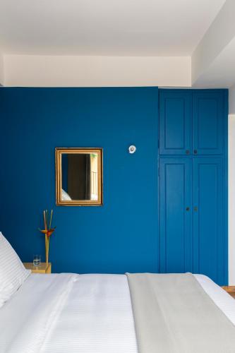 a blue bedroom with a white bed and a mirror at Nileos House in Athens