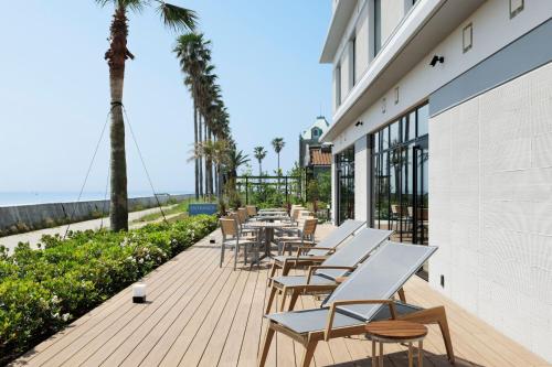 a row of tables and chairs on a deck with the beach at Fairfield by Marriott Hyogo Awaji Higashiura in Awaji