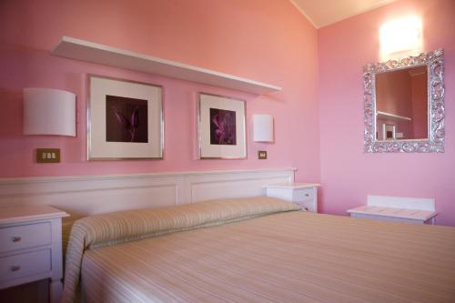 a bedroom with a bed with pink walls and a mirror at Hotel Barsalini in SantʼAndrea