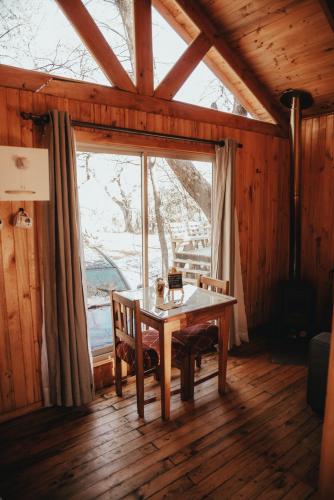a dining room with a table and a large window at Cabañas Huilipan in Las Trancas