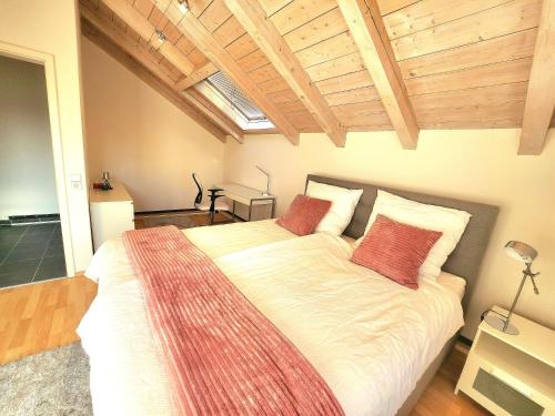 a bedroom with a large bed with two red pillows at Haus Lärche - Die Ferienwohnung in Wolfratshausen