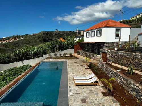 einen Pool mit zwei Liegestühlen und ein Haus in der Unterkunft CASAS DO LARANJO- Cottages & Infinity Pool in Gaula