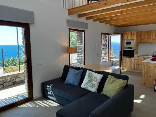 ein Wohnzimmer mit einem Sofa und einem Tisch sowie eine Küche in der Unterkunft CASAS DO LARANJO- Cottages & Infinity Pool in Gaula
