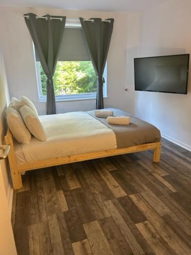 a bedroom with a bed with a television and a window at St Pauls Court Apartments in Stockton-on-Tees