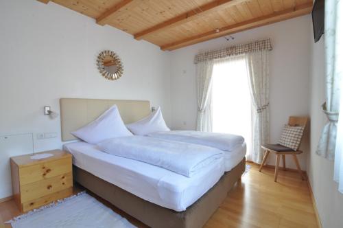 a bedroom with a bed with white sheets and a window at Hotel Traube - Stelvio in Stelvio