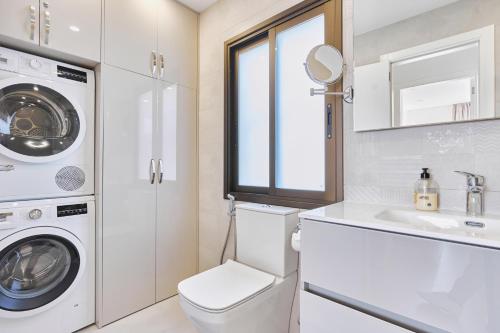 een witte badkamer met een wasmachine en een wastafel bij WINDSOR OCEAN PEARL APARTMENT in Adeje