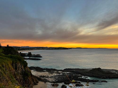 a sunset over a body of water with rocks at Jones Beach Haven Studio - Kiama Downs Beachside Escape in Kiama