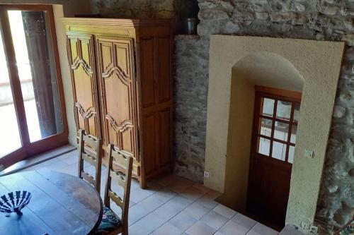 a dining room with a table and a stone wall at Loft rural - terrasse parking et vue in Ferrières-sur-Ariège