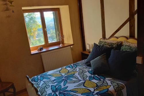 1 dormitorio con 1 cama con colcha de flores y ventana en Loft rural - terrasse parking et vue en Ferrières-sur-Ariège