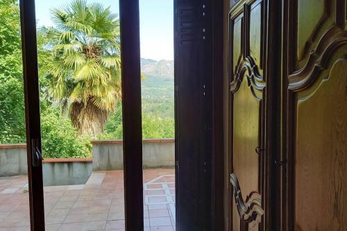 an open door with a view of a palm tree at Loft rural - terrasse parking et vue in Ferrières-sur-Ariège
