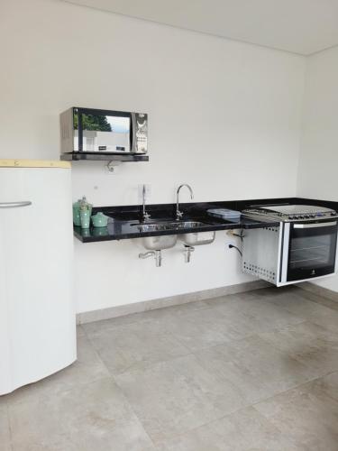 a white kitchen with a sink and a counter at Mimos Hospedagem in São Paulo
