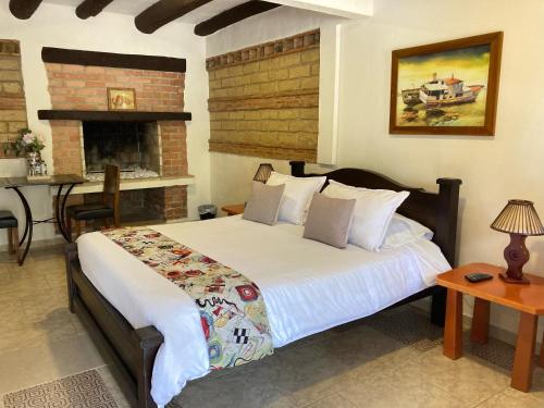 Un dormitorio con una cama grande y una chimenea. en Bombon Hotel, en Villa de Leyva