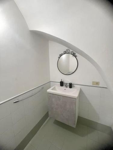 a white bathroom with a sink and a mirror at Minihome apartment in Catania