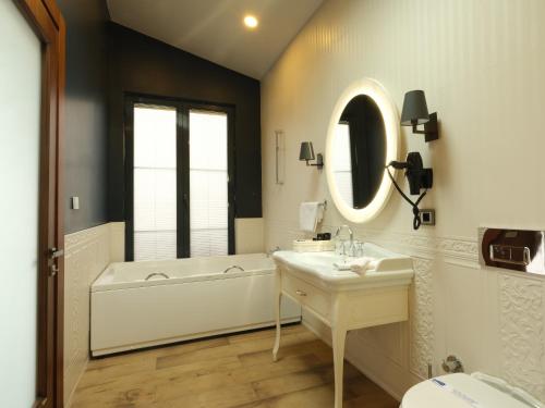 ein Badezimmer mit einer Badewanne, einem Waschbecken und einem Spiegel in der Unterkunft VİLLA POLONEZ in Istanbul