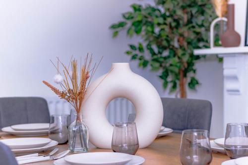 a table with a white vase and glasses on it at Templar House - Sleeps 6, Special Weekly Monthly Stay Rates, Central Location with FREE Parking, FREE WiFi, Perfect for ALTON TOWERS & M6 in Stoke on Trent