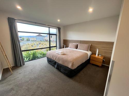 a bedroom with a bed and a large window at Ahuru Mōwai in Lake Tekapo