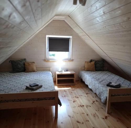 a attic bedroom with two beds and a window at Oaza Czołpino in Smołdziński Las