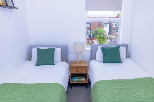 two twin beds in a room with a window at Templar House - Sleeps 6, Special Weekly Monthly Stay Rates, Central Location with FREE Parking, FREE WiFi, Perfect for ALTON TOWERS & M6 in Stoke on Trent