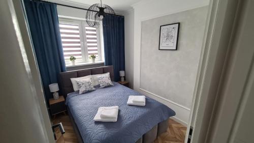een kleine slaapkamer met een blauw bed met handdoeken erop bij Apartament PRIMO in Zamość