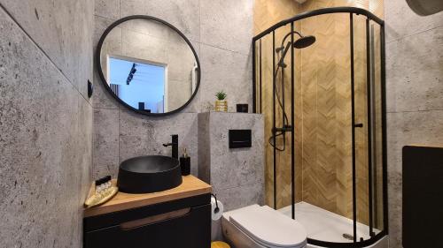 een badkamer met een douche, een toilet en een spiegel bij Apartament PRIMO in Zamość