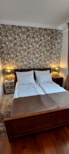 Un dormitorio con una cama grande con una pared. en Nota Apartman, en Vrnjačka Banja