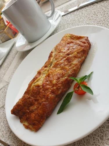 a white plate with a piece of food and a tomato at La Villa ANSALY in Sali Nianiaral