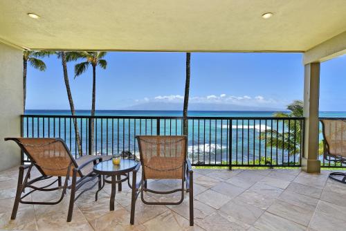un patio con tavolo, sedie e vista sull'oceano di Noelani 210 a Kahana