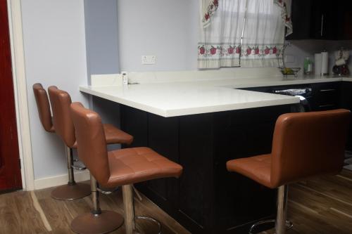 a kitchen with a black and white counter with brown stools at Pawadi Nou in Augier