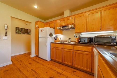 a kitchen with wooden cabinets and a white refrigerator at Elk Meadow Cabins 13A Bears Den Suite in Orick