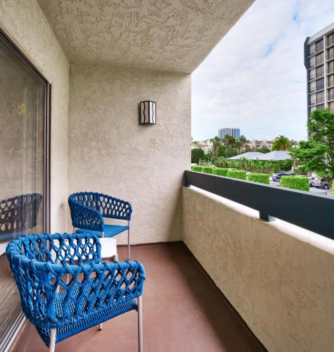 a balcony with two blue chairs and a window at Atrium Hotel Orange County in Irvine