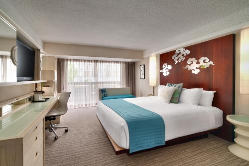 a hotel room with a large bed and a desk at Atrium Hotel Orange County in Irvine