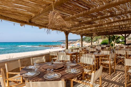 ein Restaurant mit Tisch und Stühlen am Strand in der Unterkunft Hôtel et Résidence Ta Kladia - Omigna in Cargèse