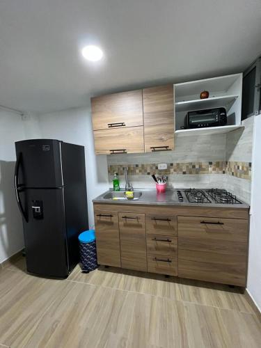 cocina con nevera negra y armarios de madera en Aparta-estudio Ciudad Jardin Norte 202, en Bogotá