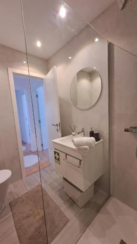 a bathroom with a sink and a shower with a mirror at SUNSET APTO in Póvoa de Varzim