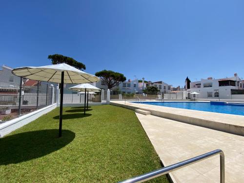 eine Liegewiese mit Sonnenschirm neben einem Pool in der Unterkunft Duplex Las Torres La Barrosa 4 Bedrooms By Chiclana Dreams - A 750 m de la playa in Chiclana de la Frontera