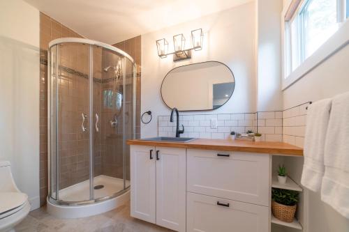a bathroom with a shower and a sink and a mirror at Cozy Cabin Suites, Sooke, Bc in Sooke