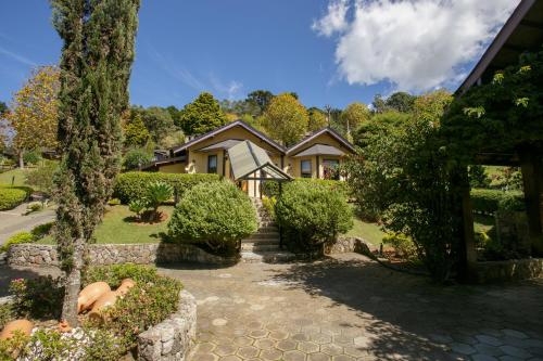 a house with a stone walkway in front of a yard at Pousada Varanda das Colinas in Monte Verde