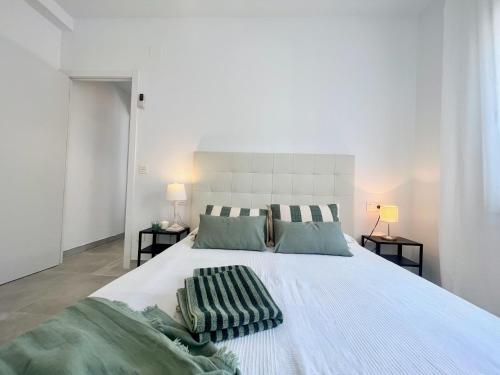a large white bed with two pillows on it at Golden Coast Calafell in El Vendrell