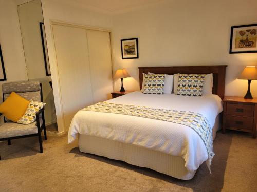 a bedroom with a large bed and a chair at Hazelwood Mapua in Mapua