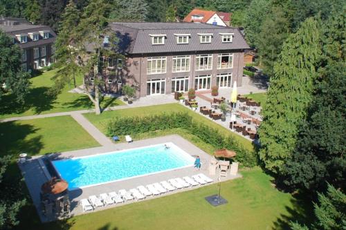 una vista aérea de una mansión con piscina en Adorable two bedroom bungalow C7 next to hotel. en Garderen