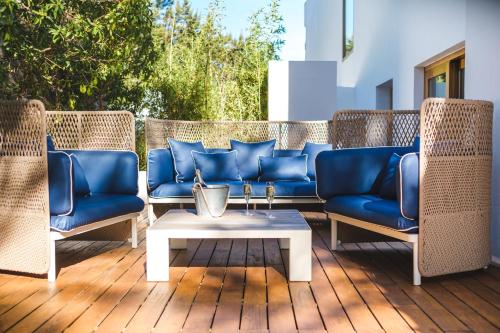 a group of blue chairs and a coffee table on a deck at Gecko Hotel & Beach Club in Playa Migjorn