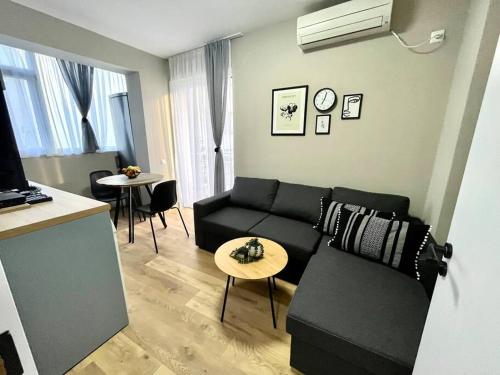 ブルガスにあるSea Garden Apartmentのリビングルーム(黒いソファ、テーブル付)