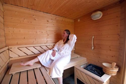 a woman is sitting in a sauna at Hotel Barsalini in SantʼAndrea