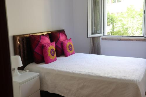 a bedroom with a bed with pink pillows and a window at Sun House Belem - Free Parking and View Tower in Lisbon